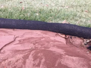 Image of a silt sock used for erosion control and sediment containment at an Apex Environmental waste disposal site.